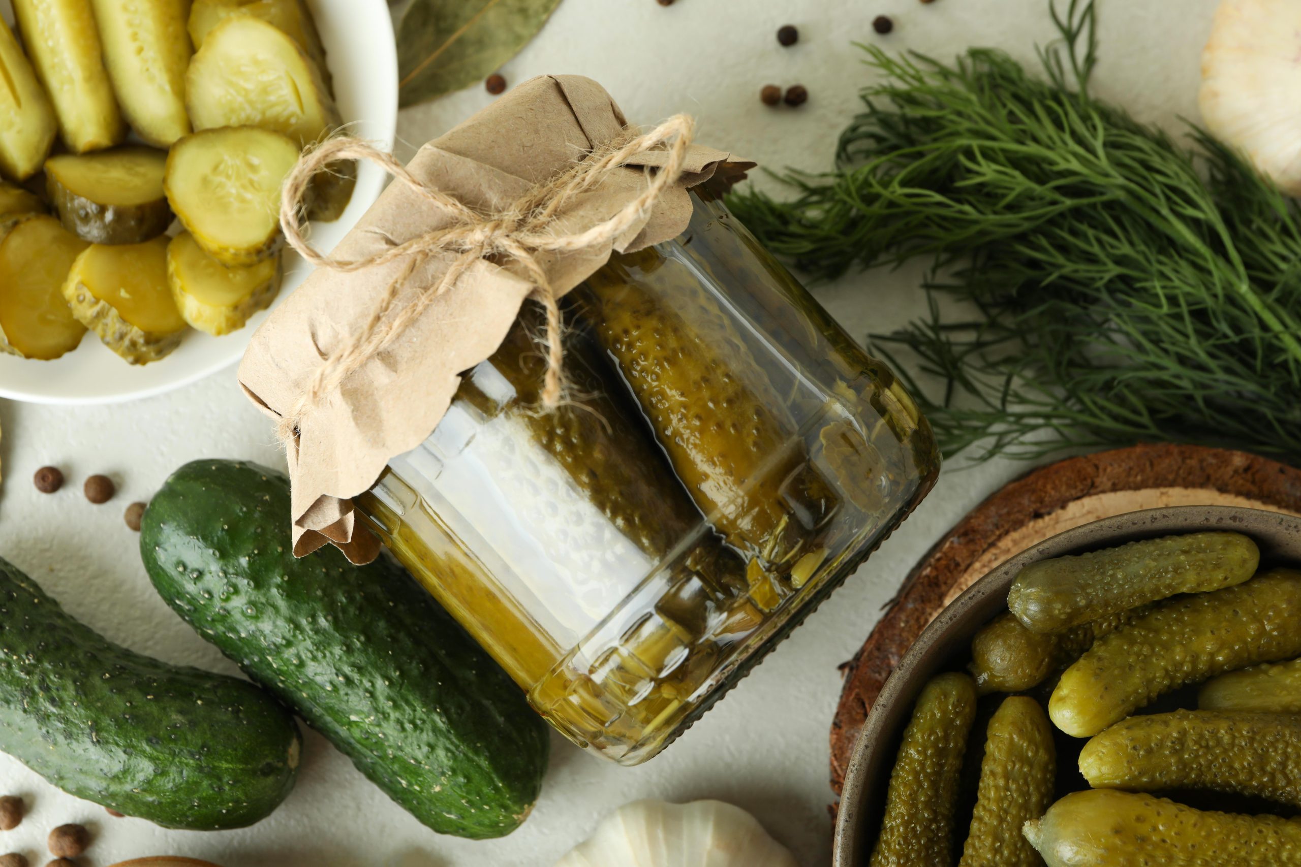 Fresh pickles and ingredients on white textured table