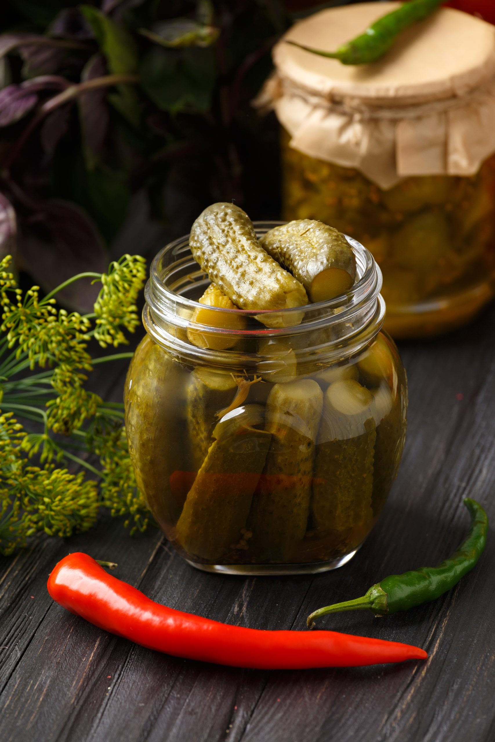 Pickled cucumbers in a jars on a dark wooden background. Homemade marinated cucumbers. Pickled cucumber salad in a jar.