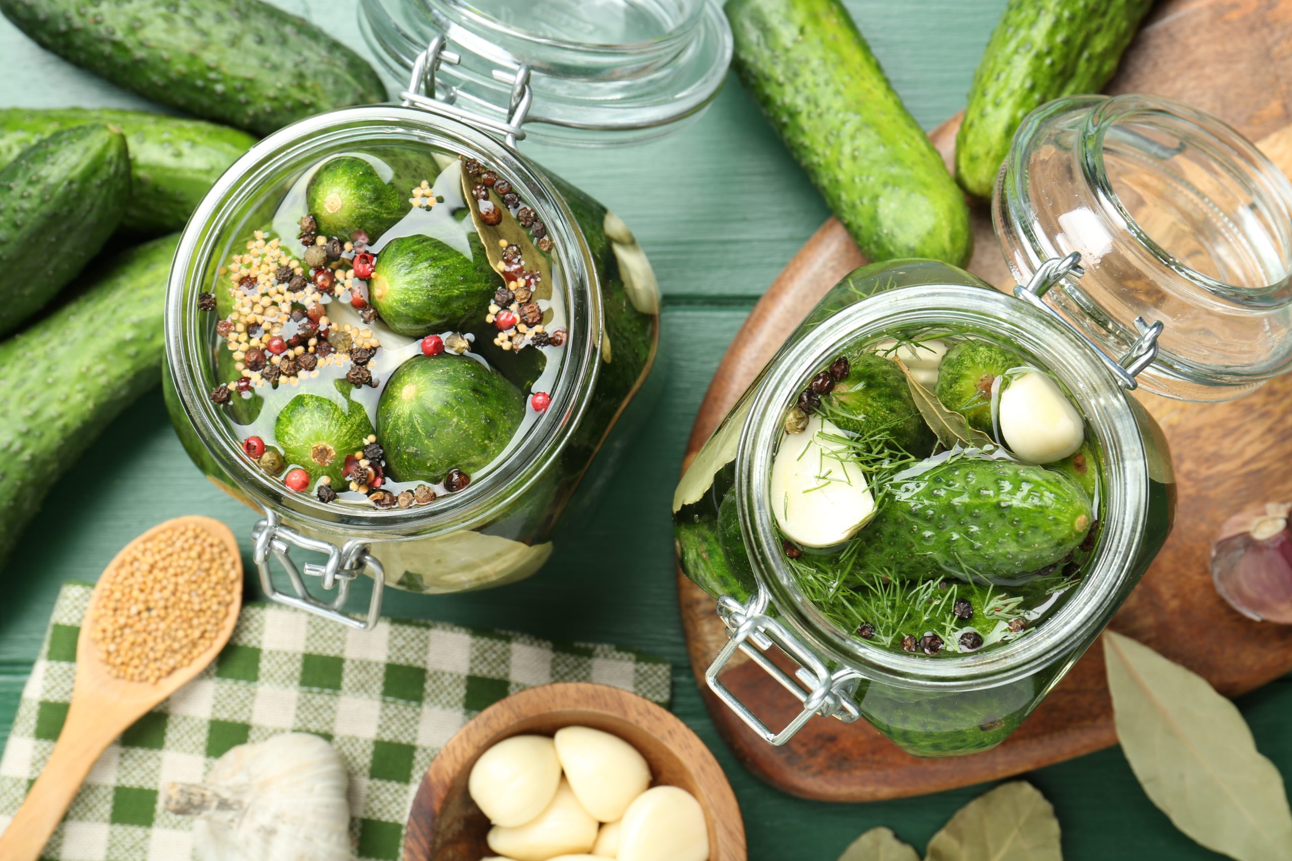 Making pickles. Fresh cucumbers and spices in jars on wooden table, flat lay